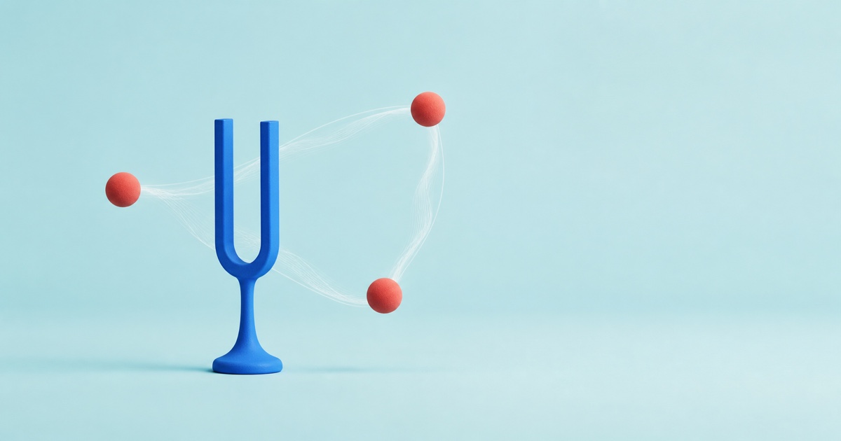 Blue tuning fork resonating with three coral spheres on a pale aqua background